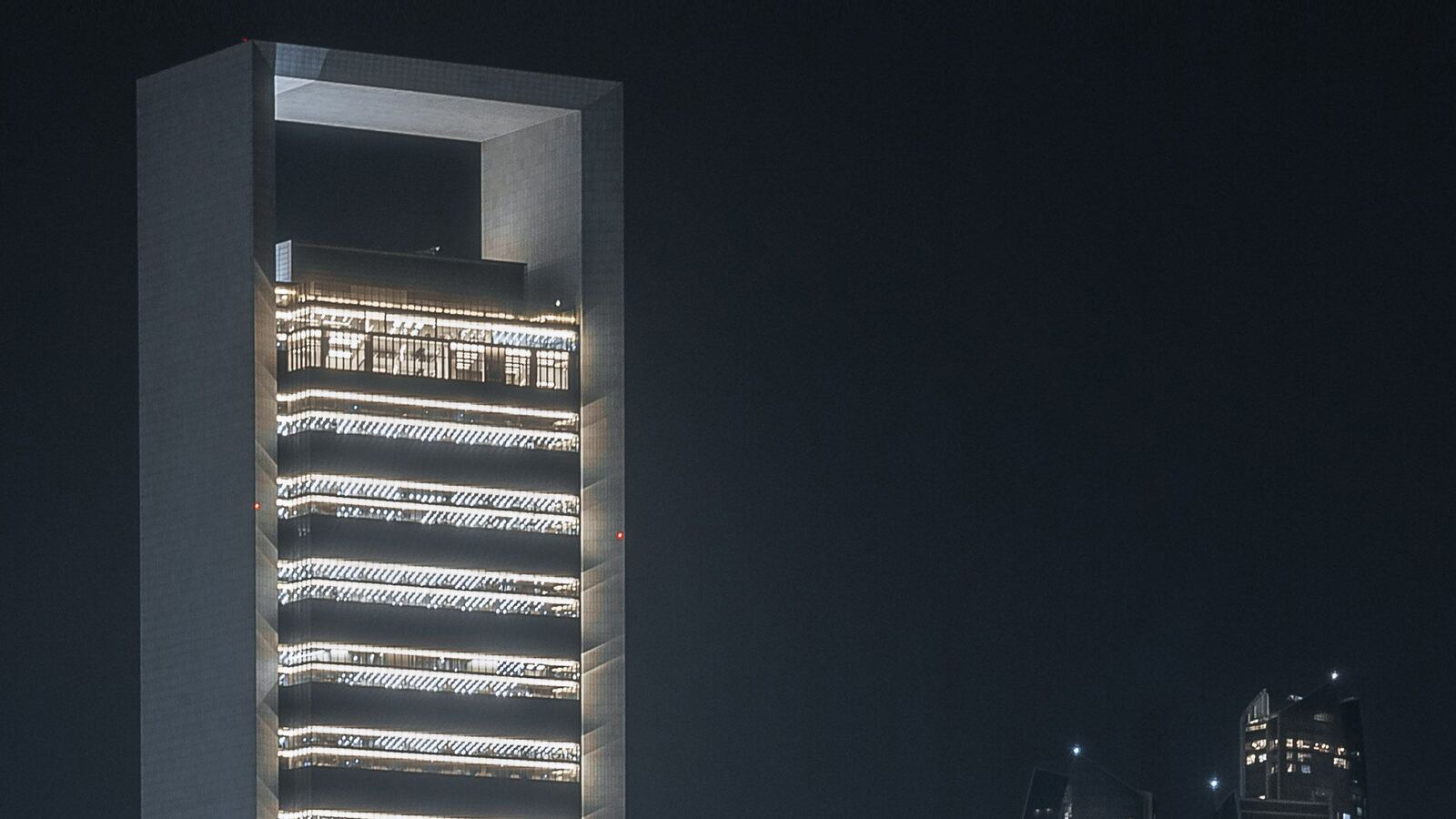 An illuminated ADNOC tower at night