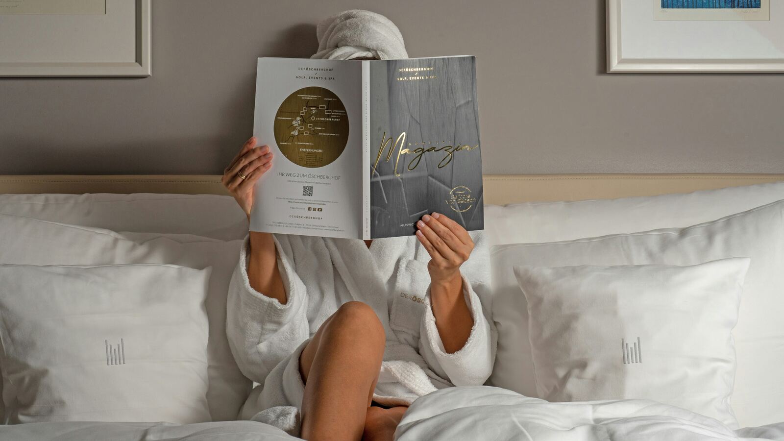 A guest reading Millennium-branded hotel collateral in a robe, Millennium pillow detail visible